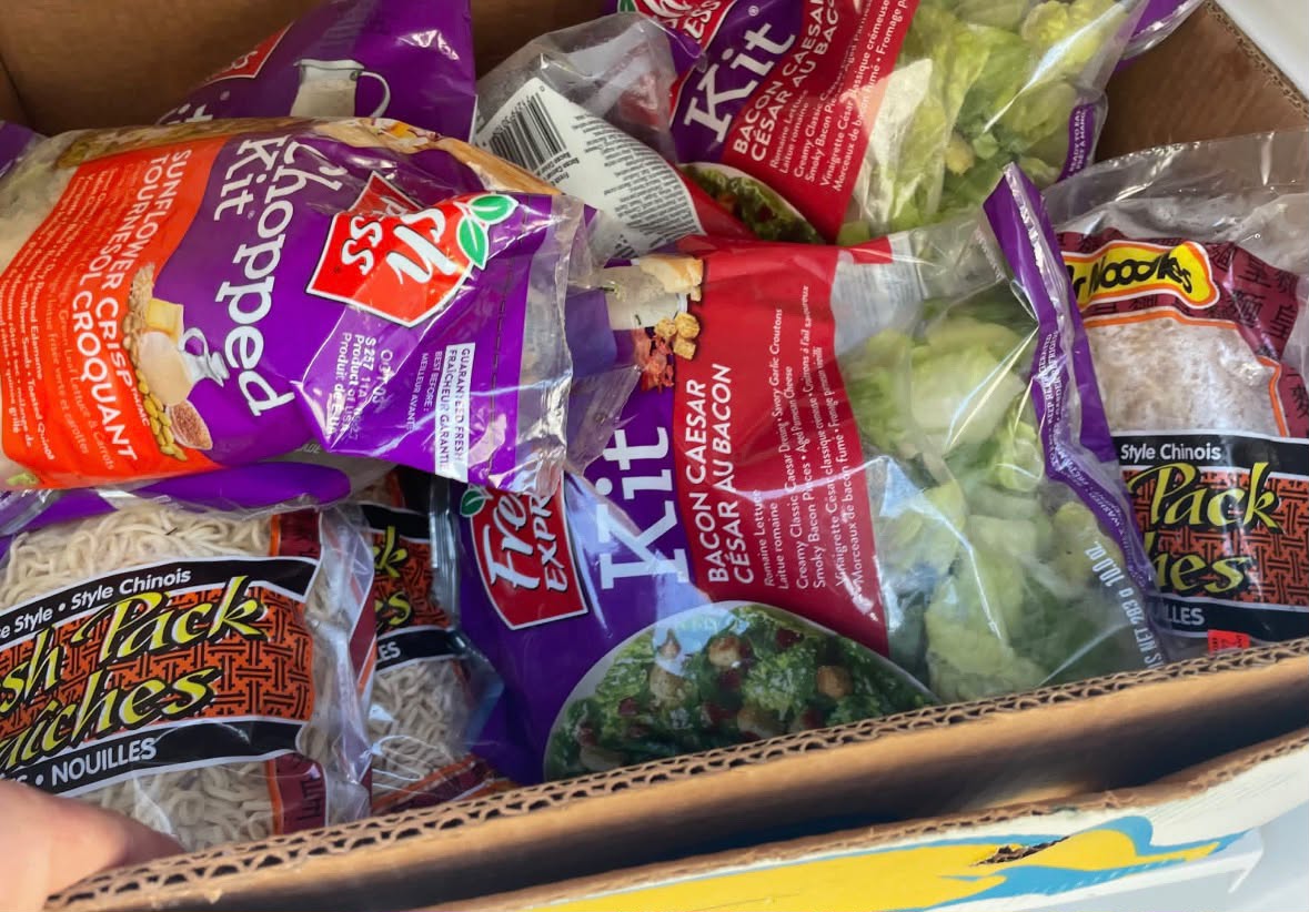 A box of salad kits and fresh noodles